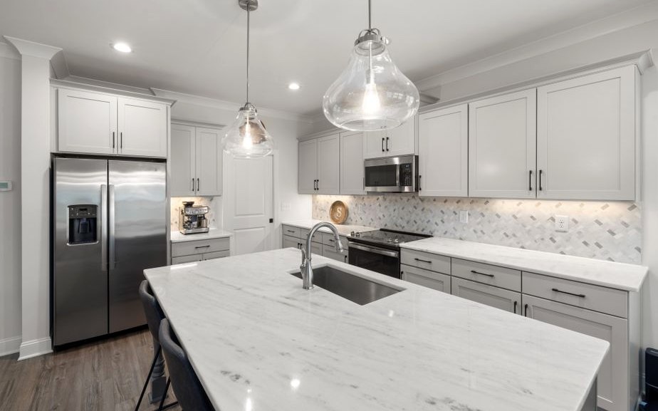 Stylish modern kitchen featuring a marble island, white cabinets, and elegant pendant lighting