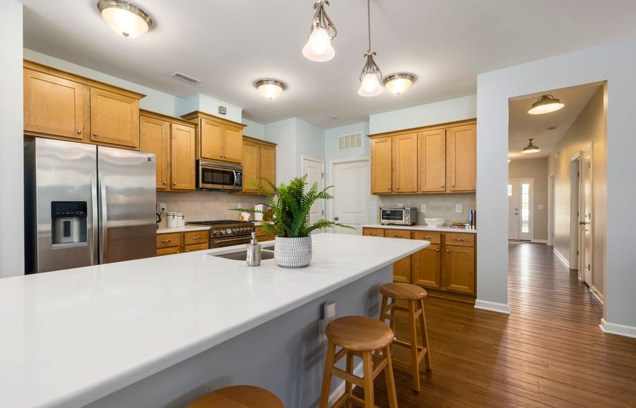 Contemporary kitchen with wooden cabinets, white countertop, and stainless steel appliances