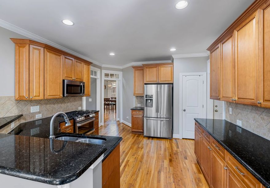 Spacious modern kitchen featuring granite countertops, wooden cabinets, and stainless steel appliances