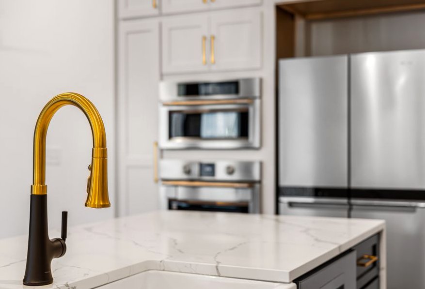 Elegant kitchen interior with a modern gold faucet and sleek stainless steel appliances
