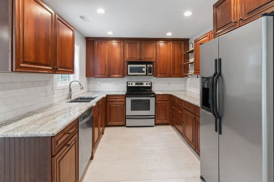 Spacious kitchen featuring stainless steel appliances, wooden cabinets, and granite countertops